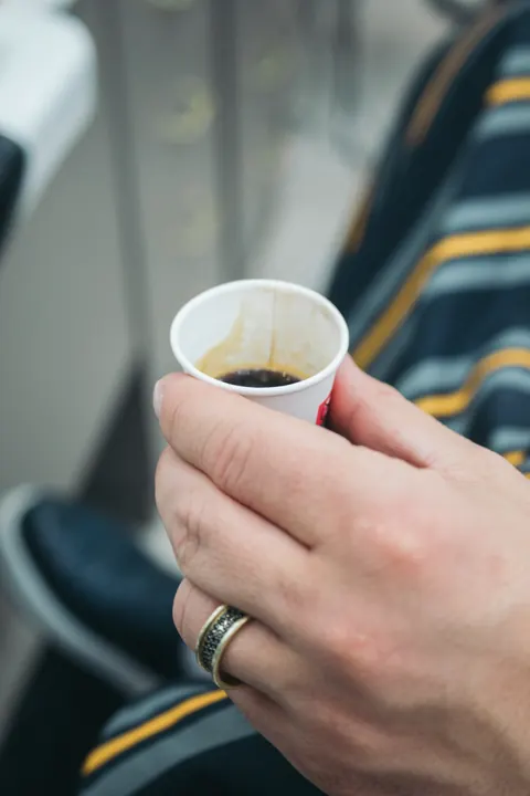 Klient drží pohár kávy počas návštevy holičstva