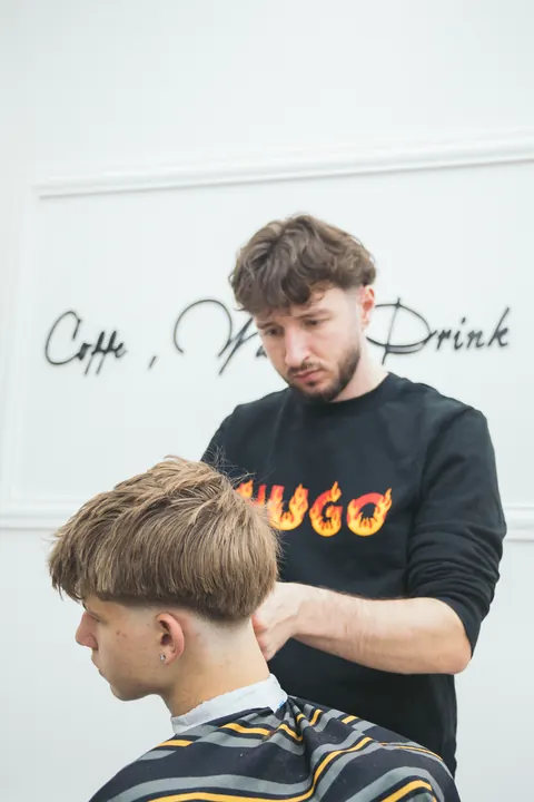 Barber upravuje strih mladému klientovi